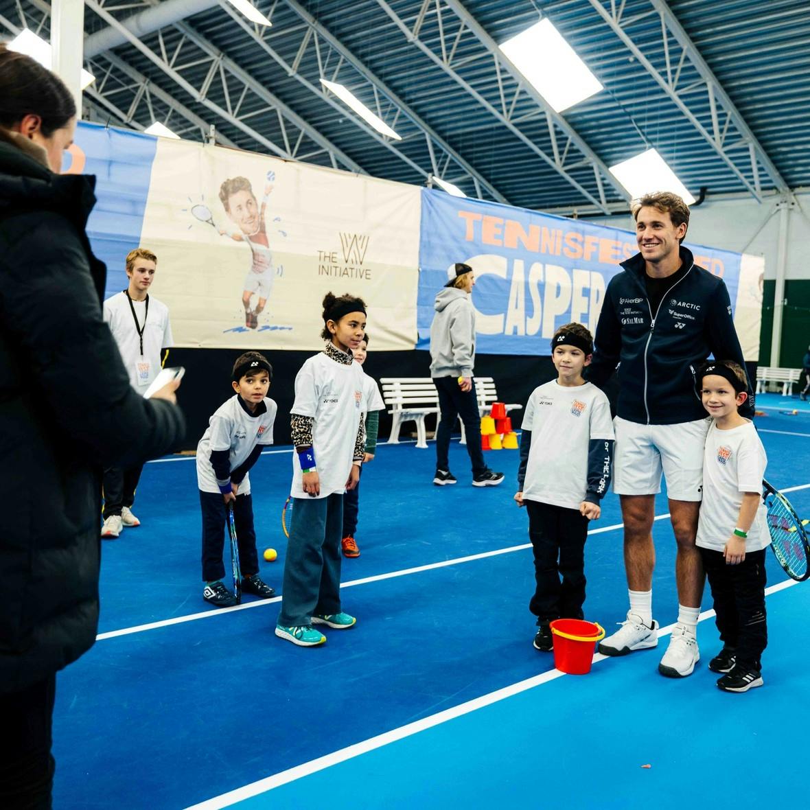 Tennisspiller Casper Ruud tar bilder med to barn på en innendørs tennishall i Trondheim