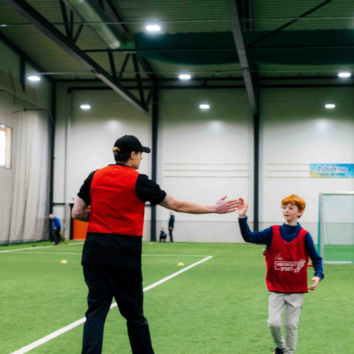 Gustav Magnar Witzøe gir en high five til et barn på innendørs fotballbane